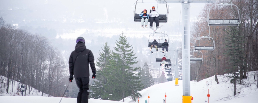 Skiers on the Chairlift and a skier on the slopes overlooking the valley at The Highlands