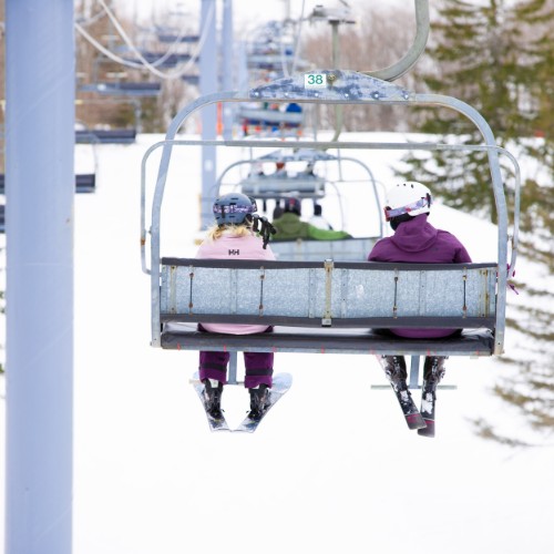 Two skiers sitting on a chairlift at The Highlands